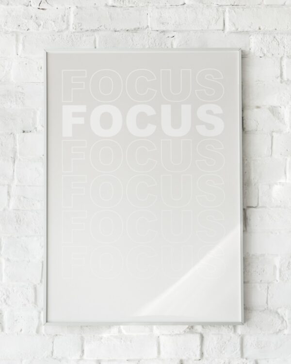 Minimalistisk plakat med ordet “FOCUS” gentaget i falmede hvide nuancer på en ren baggrund. Inspirerer til koncentration og ro.
