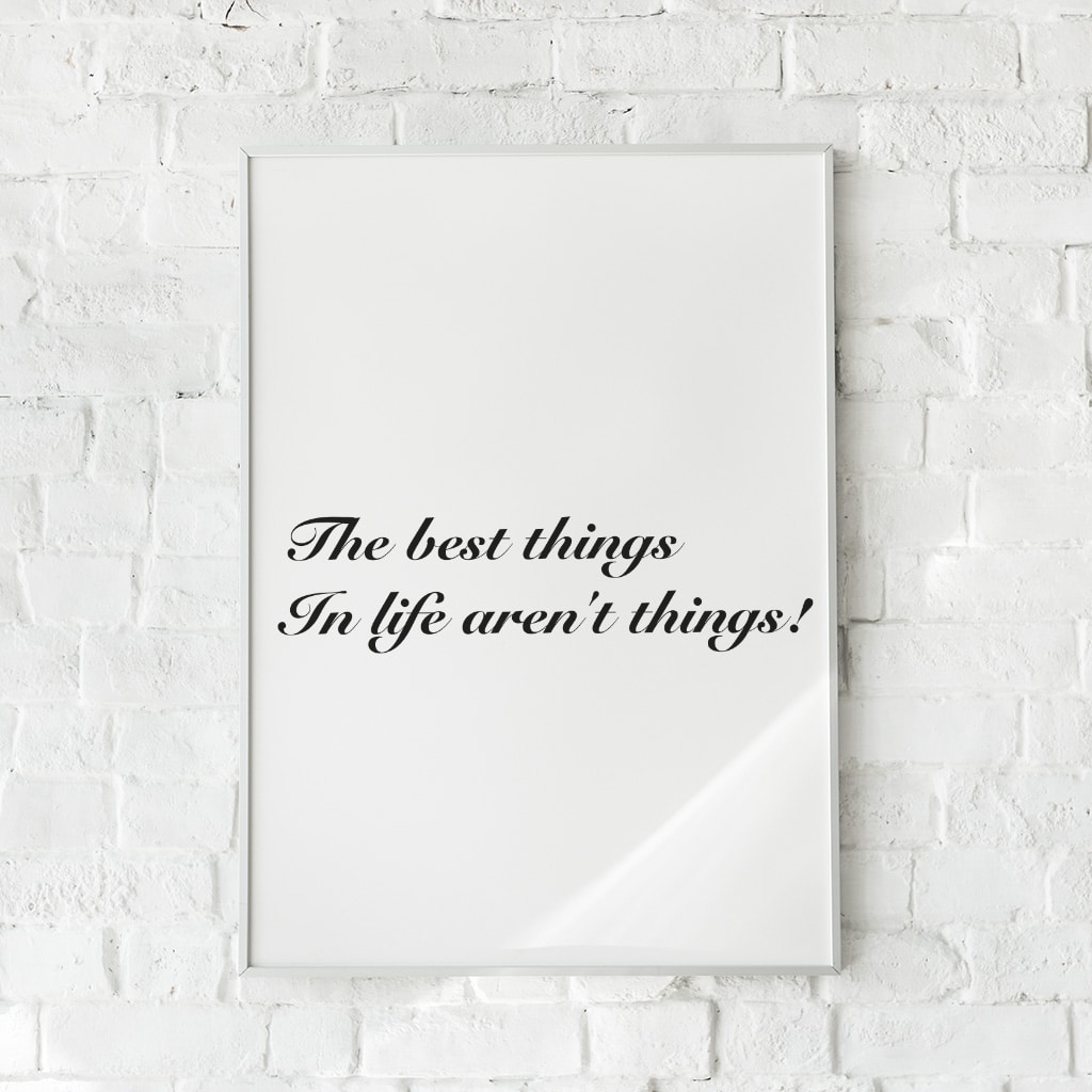 Hvid plakat med sort tekst: “The best things in life aren’t things!”, hængende på hvid murstensvæg.